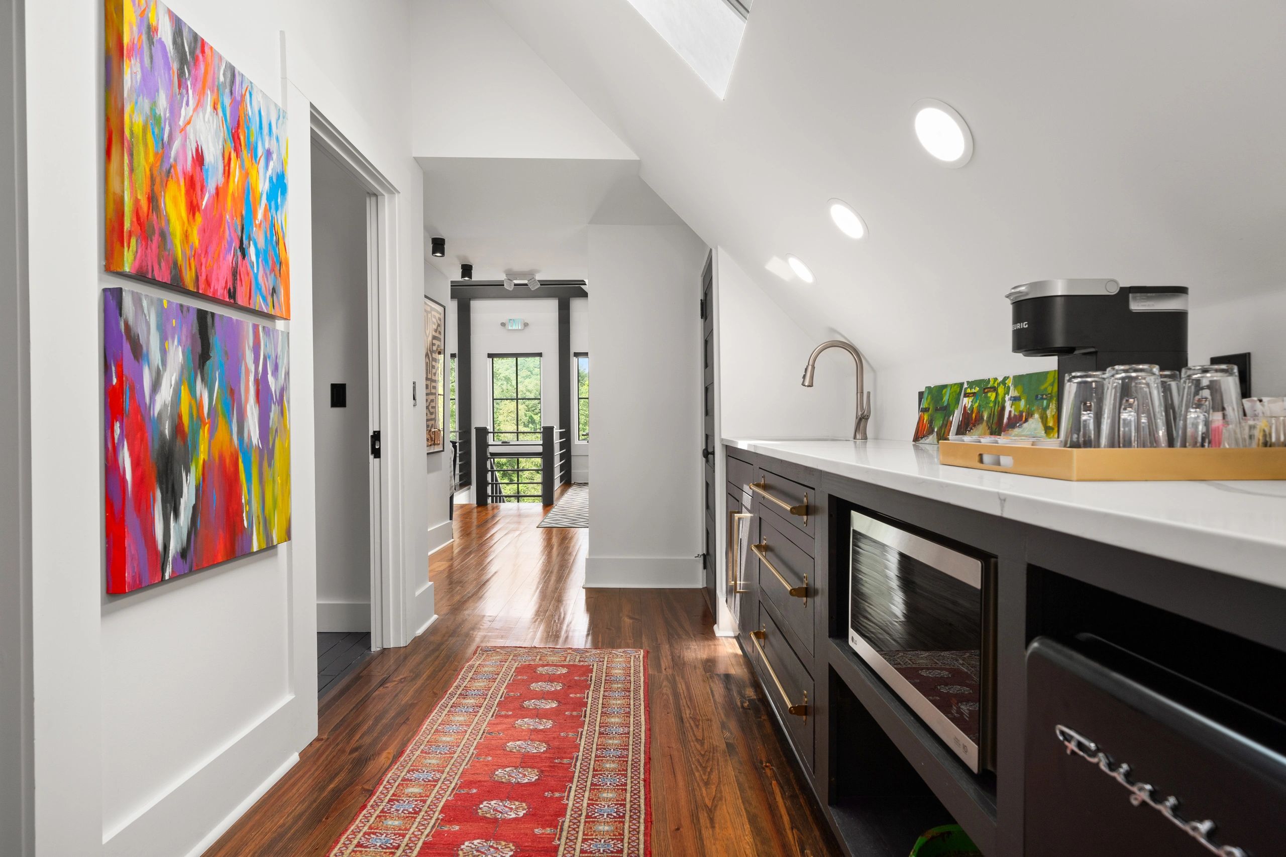 Modern kitchen area with colorful paintings and wooden floor